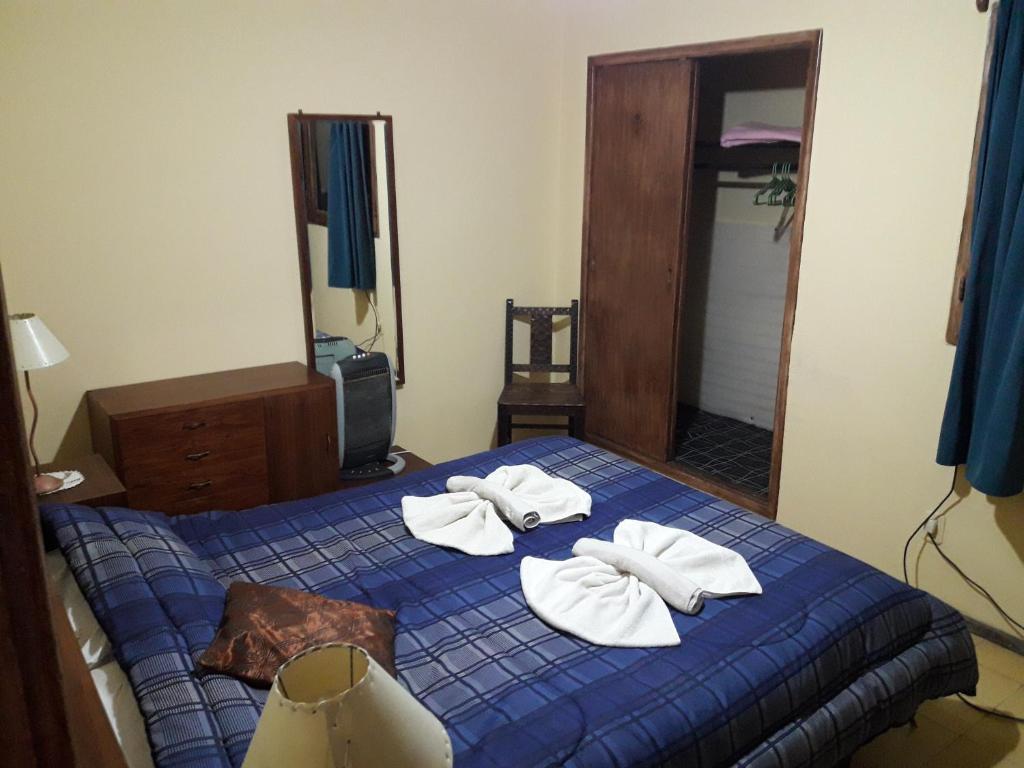 ein Schlafzimmer mit einem blauen Bett und Handtüchern darauf in der Unterkunft Casa en Las Sierras de Cordoba in La Falda