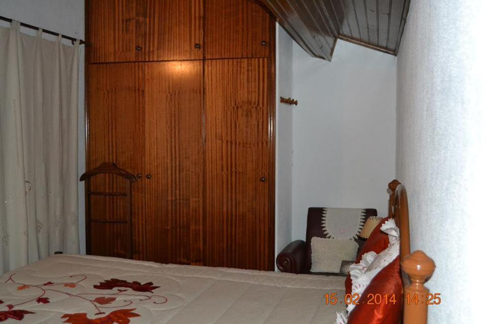1 dormitorio con 1 cama y armario de madera en Casa da Maria en Monsanto