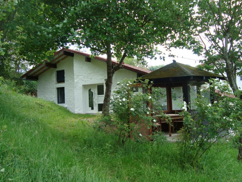 una casa blanca con un cenador en una colina en Gite de Moulin Maurt en Xertigny