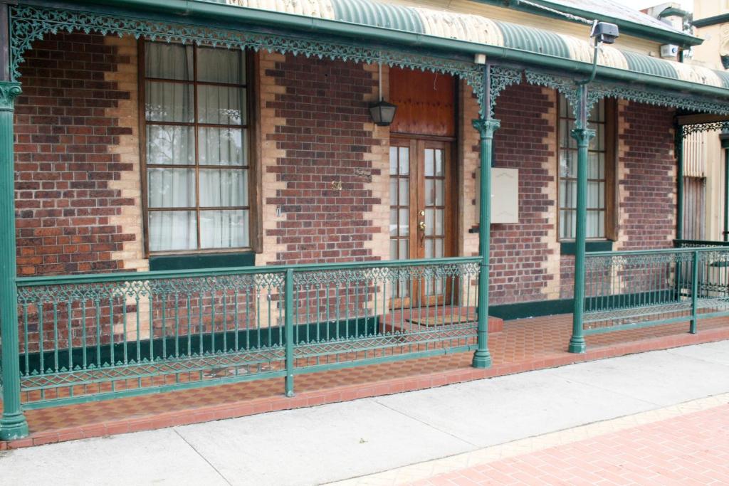 a brick building with a green fence next to a sidewalk at 34 on Emily in Seymour