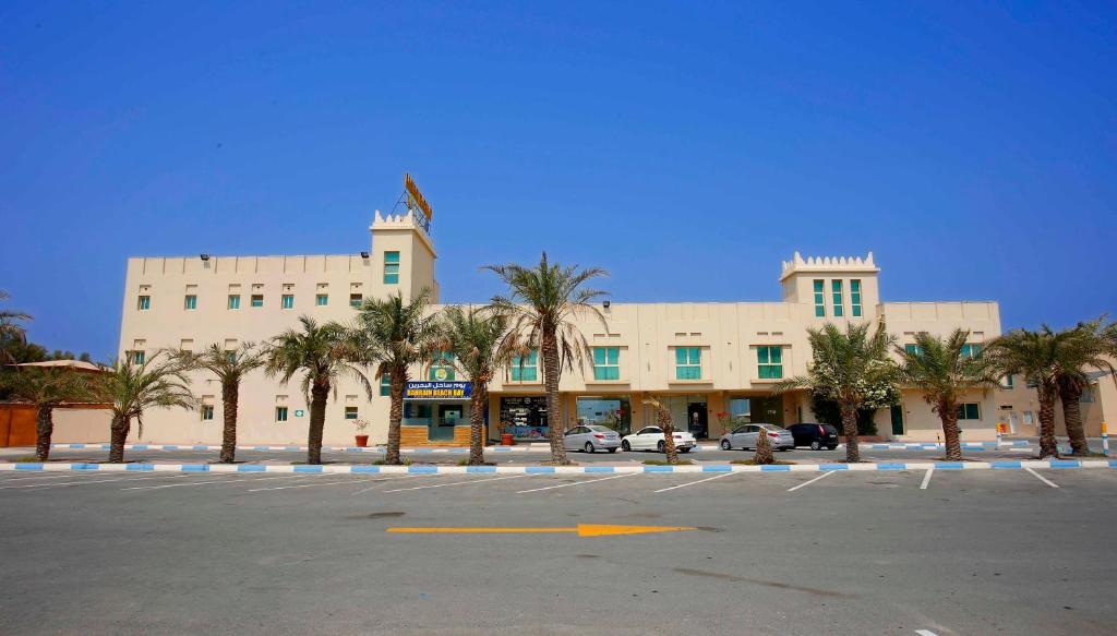 a large building with palm trees in a parking lot at Bahrain Beach Bay in Az Zallāq