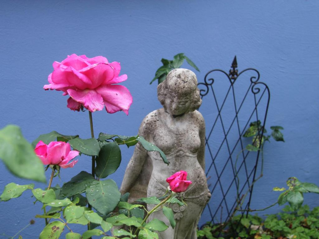 una estatua de un niño sosteniendo una flor rosa en No.31 B&B im Rosengarten en Kapellen-Drusweiler