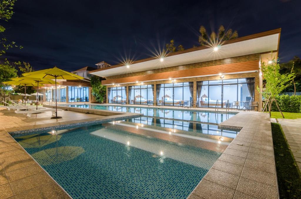 uma piscina em frente a uma casa à noite em Golf Inn Resort em Samut Songkhram