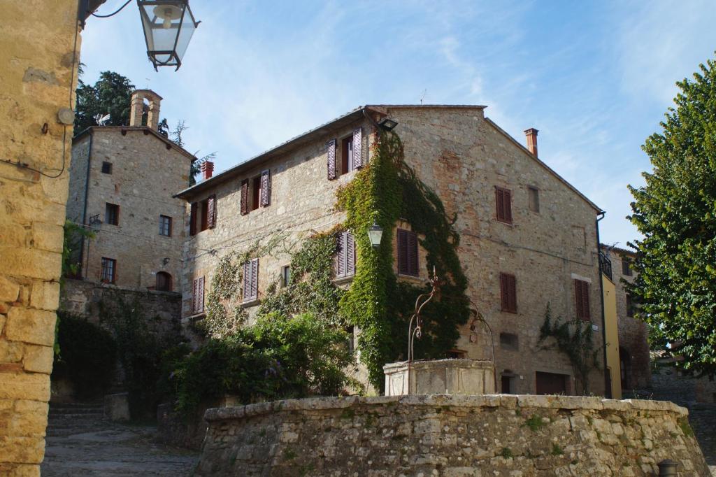 Ein altes Steingebäude, auf dem Efeu wächst. in der Unterkunft La Mandola in Castiglione dʼOrcia