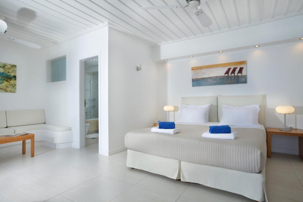 a white bedroom with a large bed with blue pillows at Selana Suites in Chrisopigi
