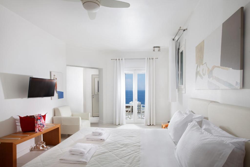 a white room with a bed and a view of the ocean at Selana Suites in Chrisopigi