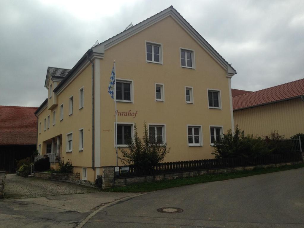 ein großes gelbes Gebäude mit einer Flagge darauf in der Unterkunft Jurahof Wuermser in Denkendorf