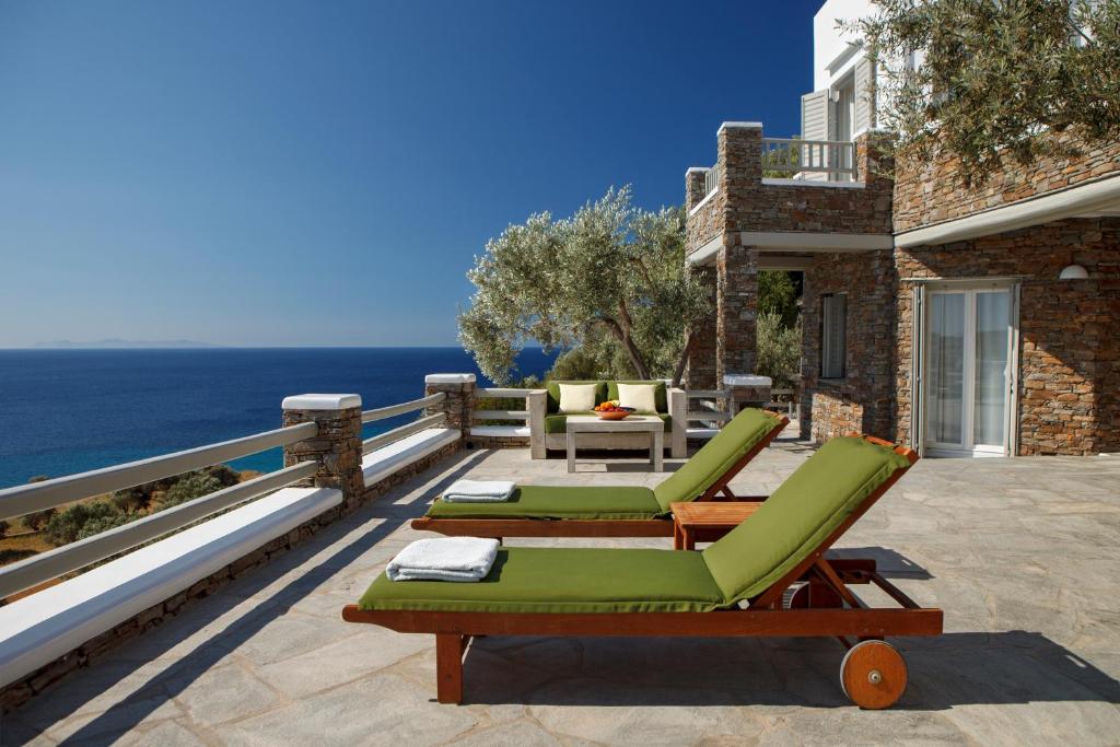 a patio with chaise lounge chairs and the ocean at Selana Suites in Chrisopigi