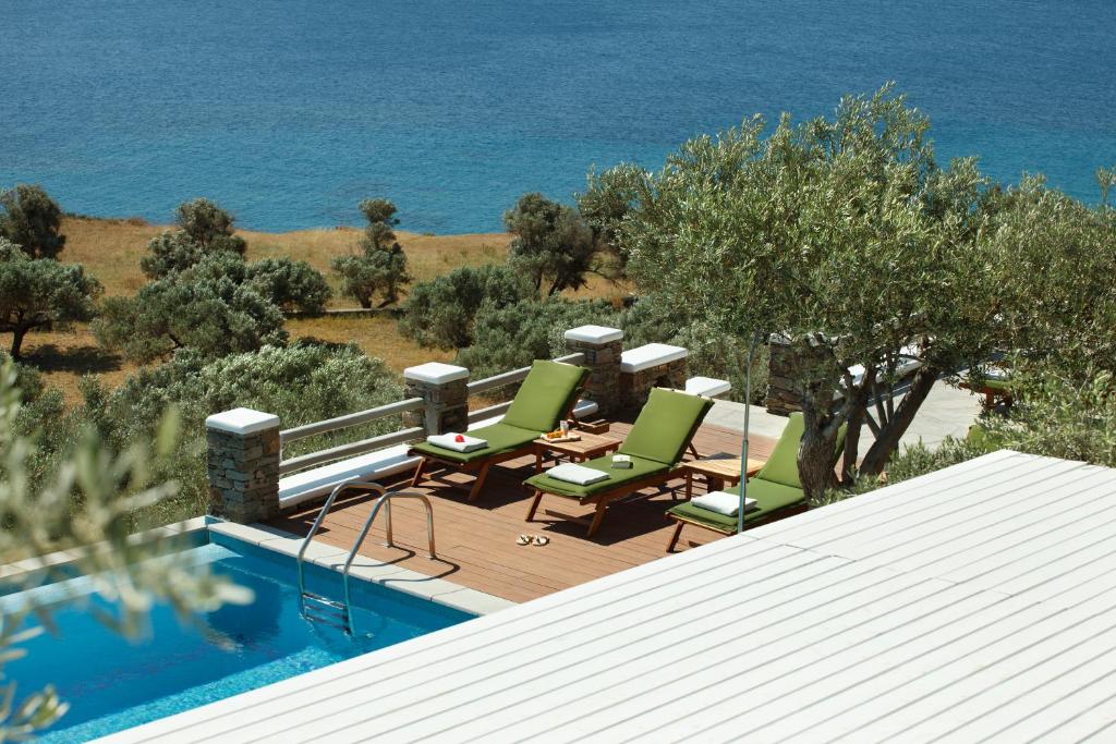 a pool with chairs and a table next to the ocean at Selana Suites in Chrisopigi