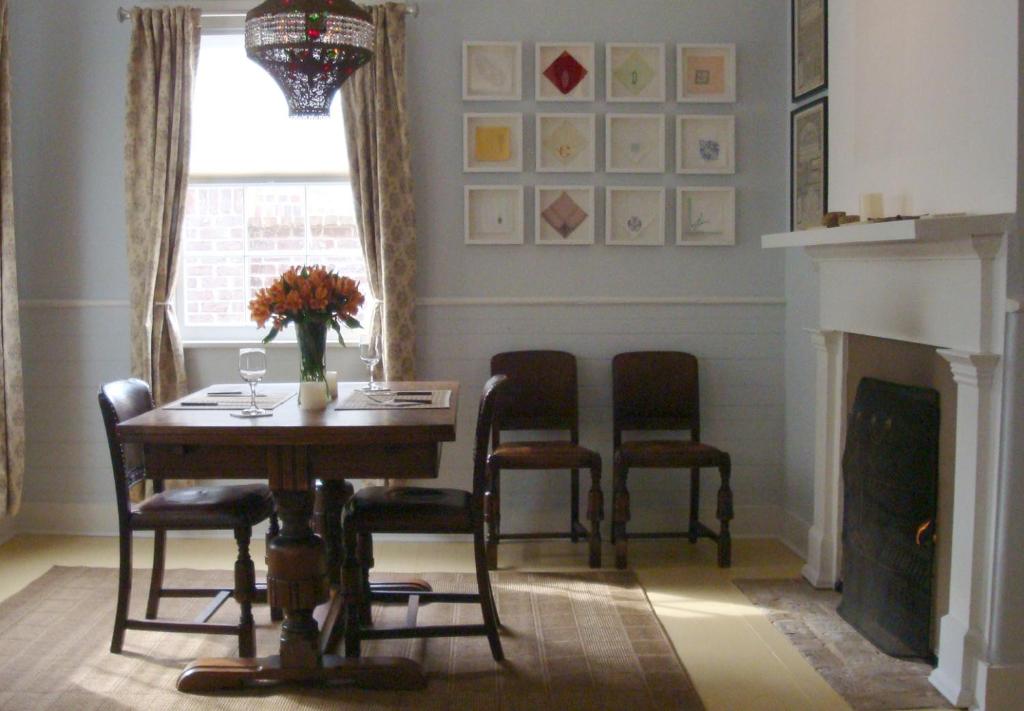 a dining room with a table and chairs and a fireplace at Jingle Bells Square Cottage-Historic District-Bright- Fireplace in Savannah