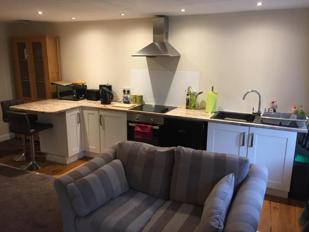 a living room with a couch and a kitchen at Winwood Apartment in Holmfirth