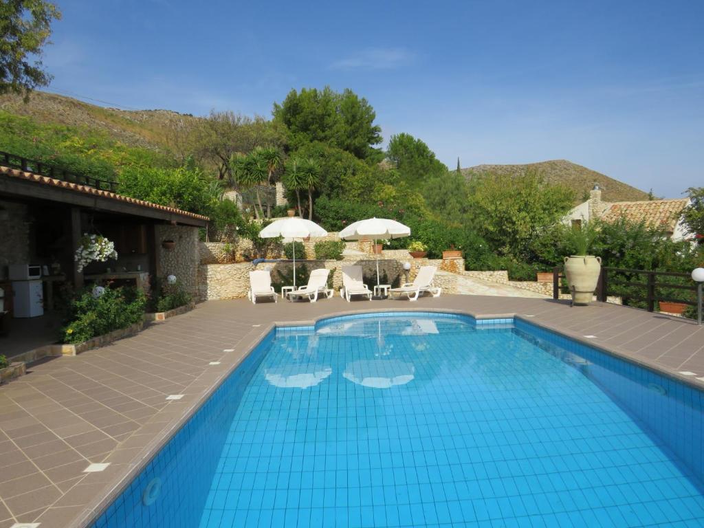 une piscine avec chaises et parasols sur un patio dans l'établissement Casale Giulietta, à Scopello