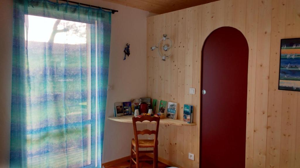 a room with a chair and a shelf and a window at Les Chênes Bleus in Sainte-Marie-de-Ré