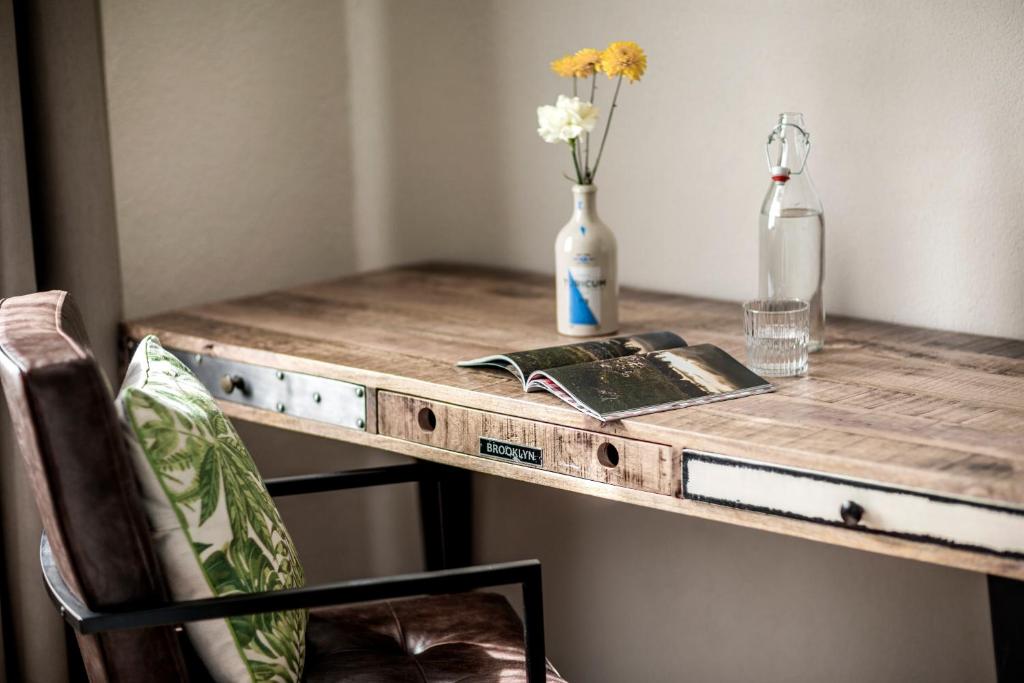 a wooden table with a book and a vase with flowers at The Yard Zürich in Zurich