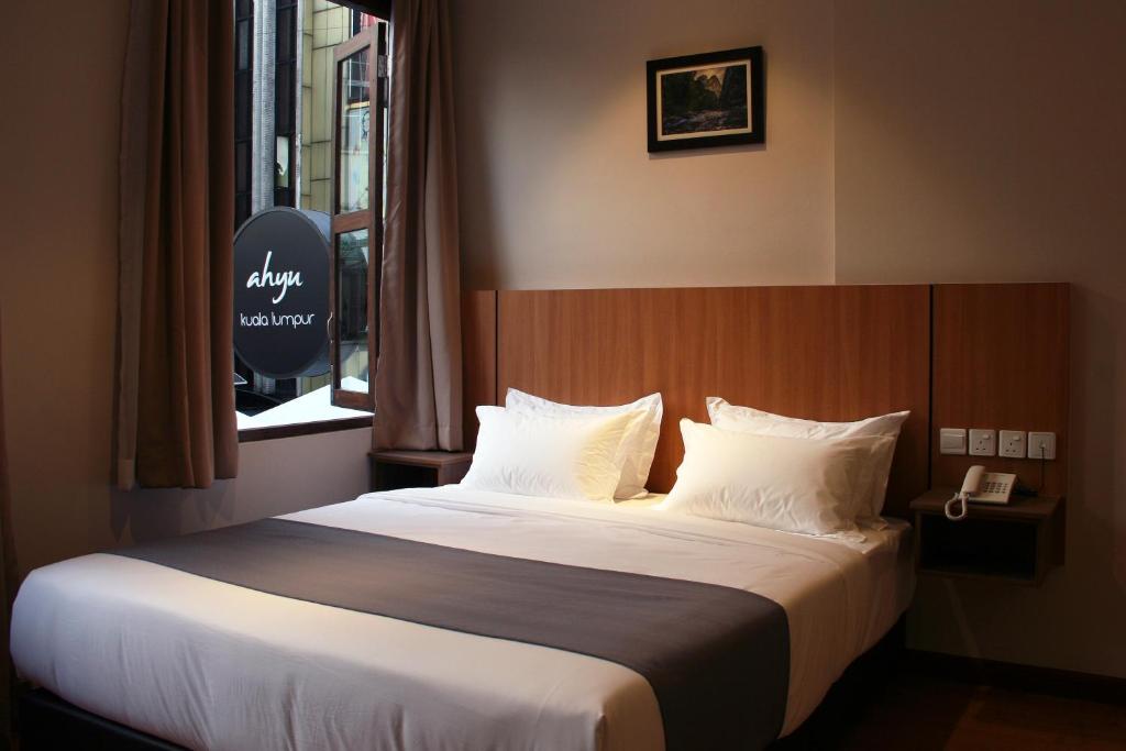 Schlafzimmer mit einem Bett mit weißer Bettwäsche und einem Fenster in der Unterkunft Ahyu Hotel in Kuala Lumpur