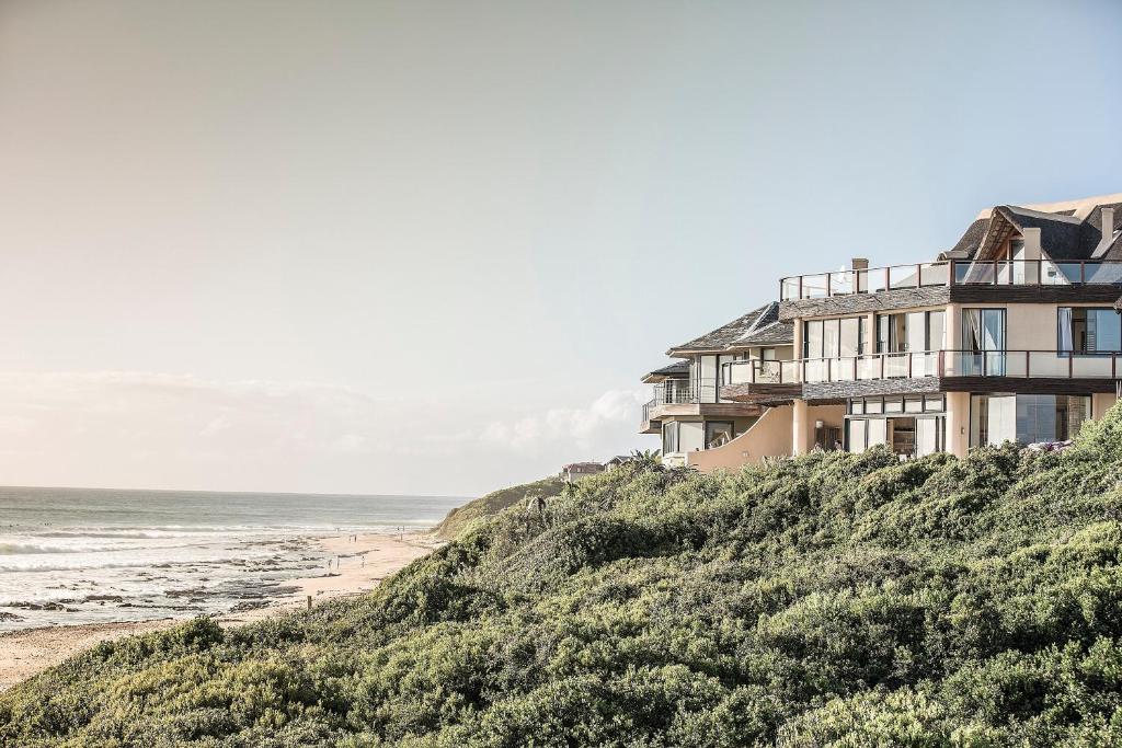 a house on a hill next to the beach at Dolphin Sunrise in Jeffreys Bay