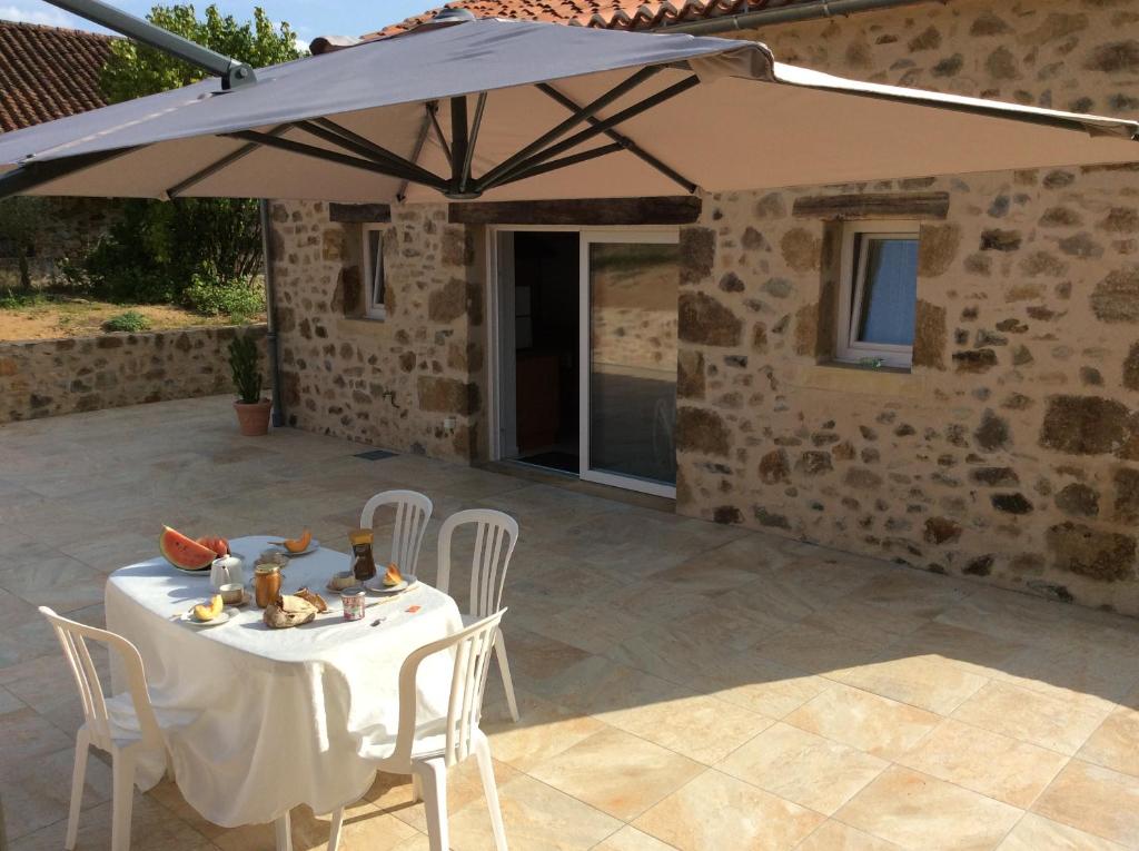 a table and chairs under an umbrella on a patio at Gîte Des Vergnes in Esse