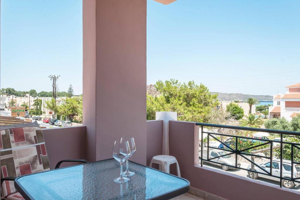 uma mesa com dois copos de vinho numa varanda em Nikos Apartments em Agia Marina Nea Kydonias
