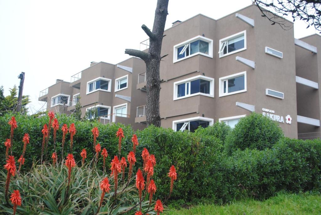 a building with red flowers in front of it at Complejo Sakura in Villa Gesell