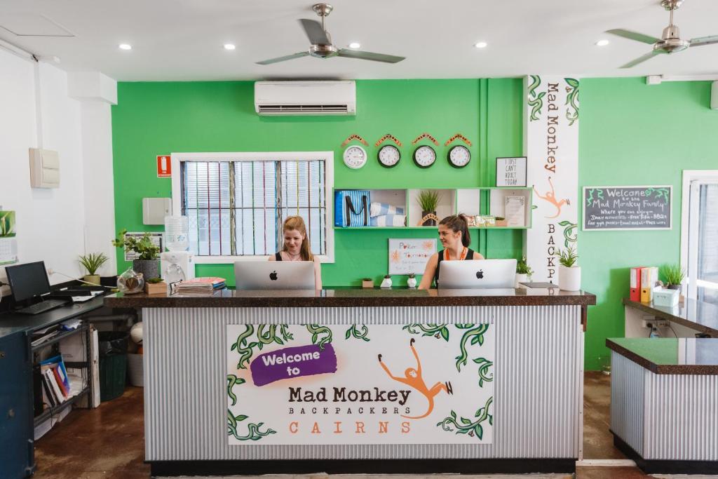 dos mujeres sentadas en un mostrador con sus ordenadores portátiles en Mad Monkey Central, en Cairns