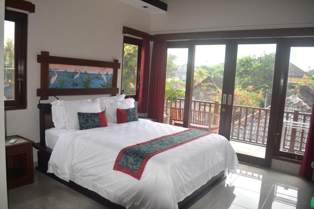 a bedroom with a bed and a balcony with windows at Manik House in Ubud