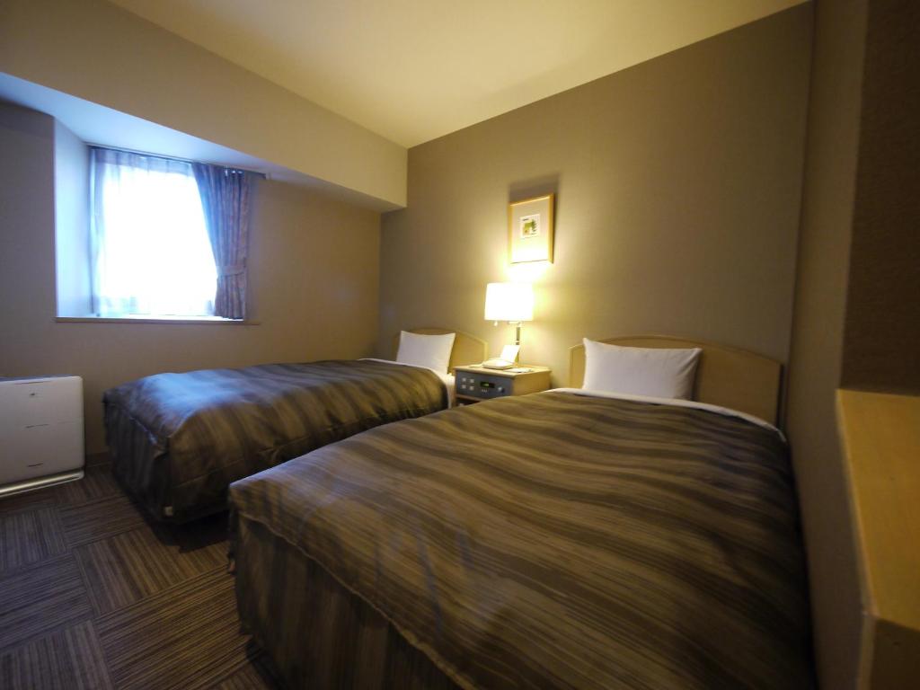 een hotelkamer met 2 bedden en een raam bij Hotel Route-Inn Hakata Ekiminami in Fukuoka