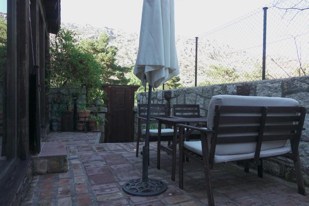 una mesa y sillas con una sombrilla en el patio en Las Horas Perdidas, en Manzanares el Real