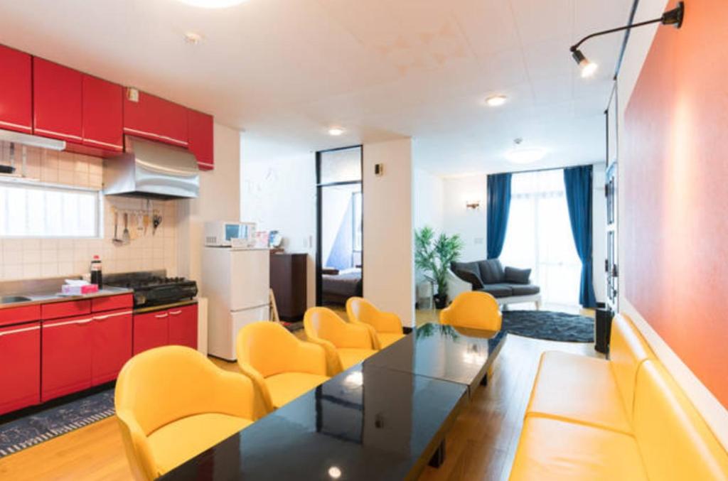 eine Küche und ein Wohnzimmer mit einem Tisch und gelben Stühlen in der Unterkunft Holiday Homes TSUBOYA 1st in Naha