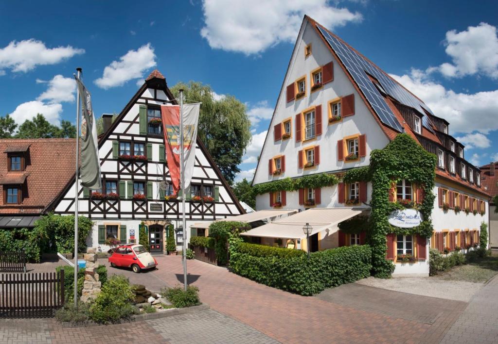 un bâtiment avec une voiture rouge garée devant lui dans l'établissement Hotel Restaurant Lohmühle, à Bayreuth