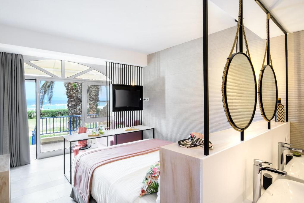 a hotel room with a bed and a balcony at Antigoni Seaside Resort in Ormos Panagias