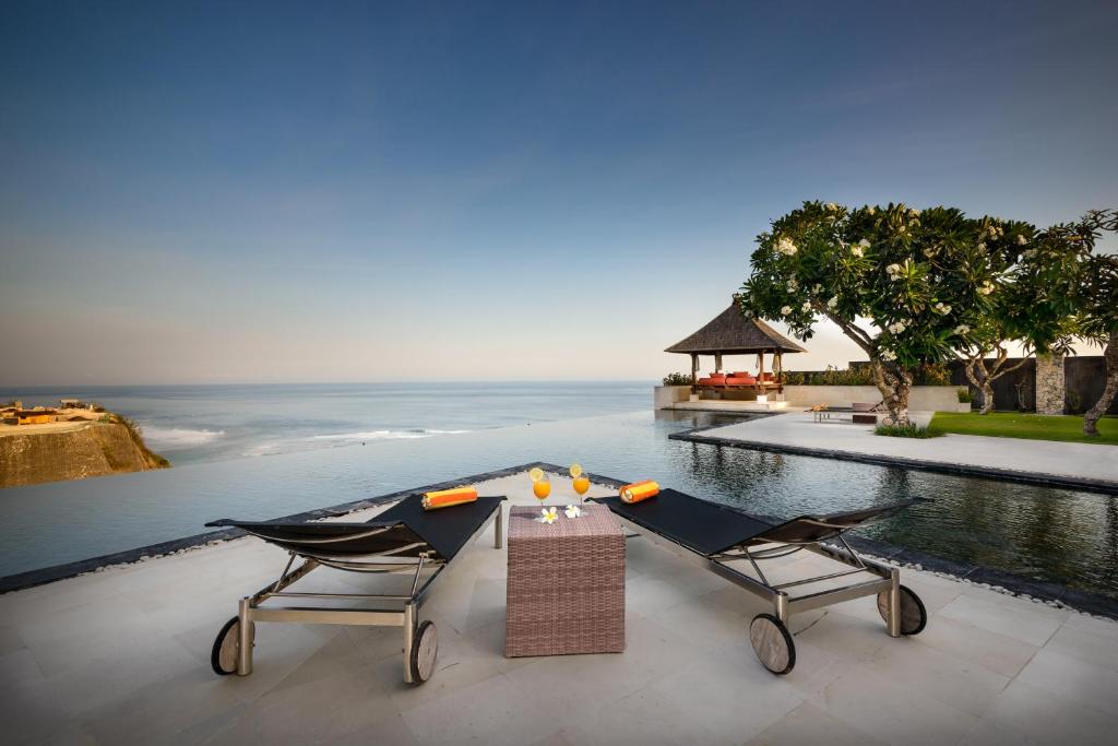 a patio with a table and two chairs and the ocean at Villa Karang Kembar 3 in Uluwatu