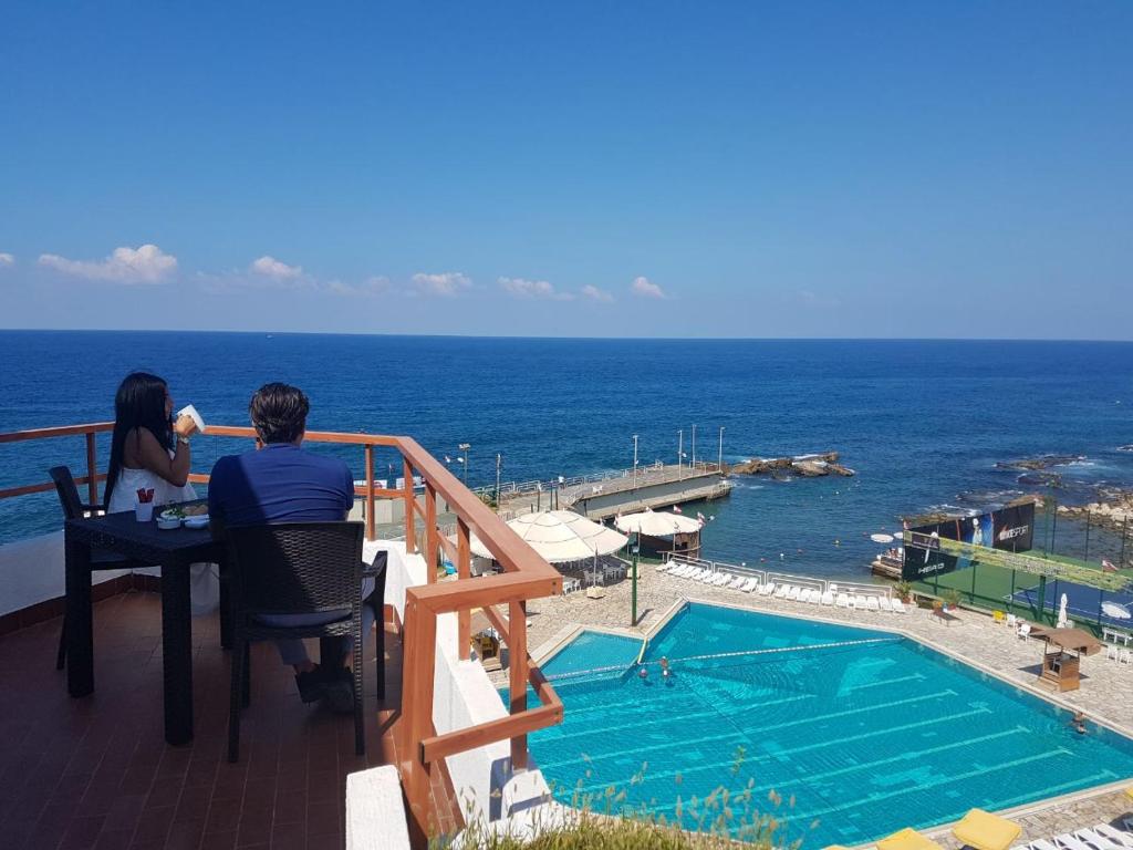 een man en vrouw aan een tafel naast een zwembad bij Cimer SafraMarine Beach Resort in Safra