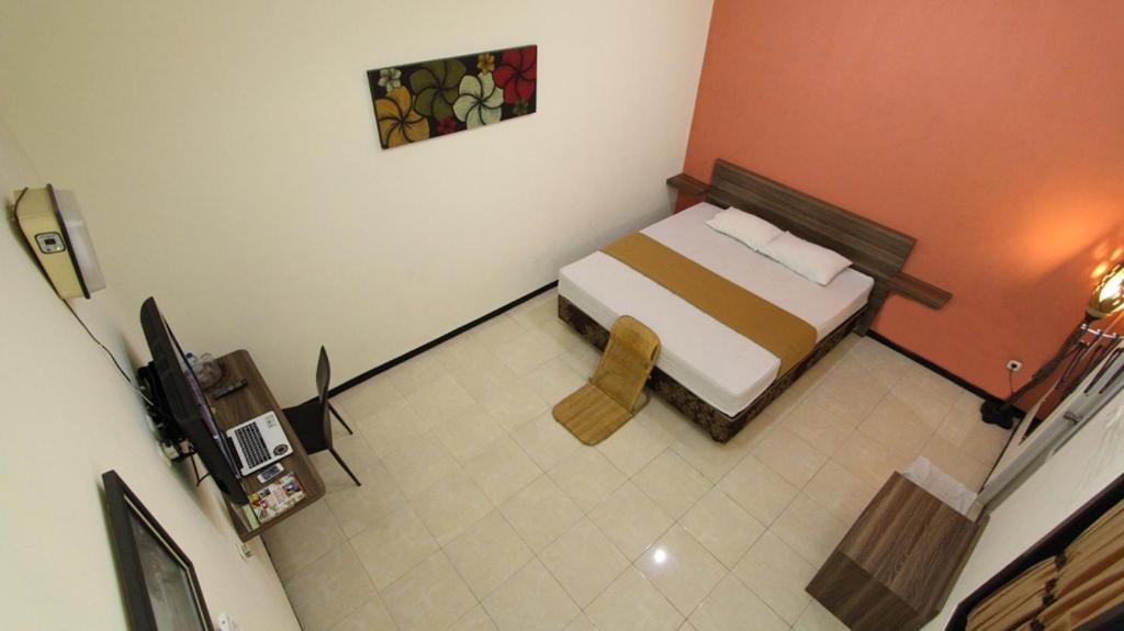 a small room with a bed and a television at Guest House Rumah Wahidin Syariah in Probolinggo