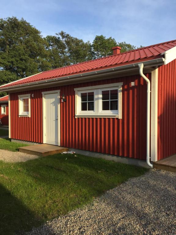 a red house with a white door and a window at Hallagårdens stugby in Varberg