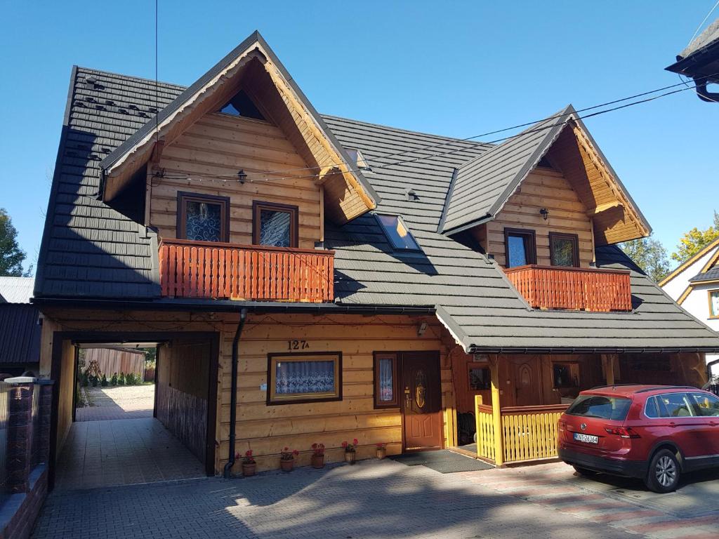 una casa con tetto a foglia d'azzardo con un'auto parcheggiata di fronte di Pokoje u Bogusi a Chochołów