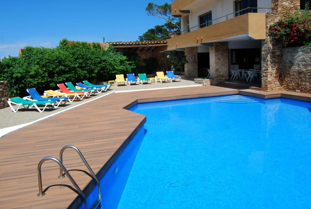 a swimming pool with a blue chair and blue chairs at Hotel Sa Riera in Begur