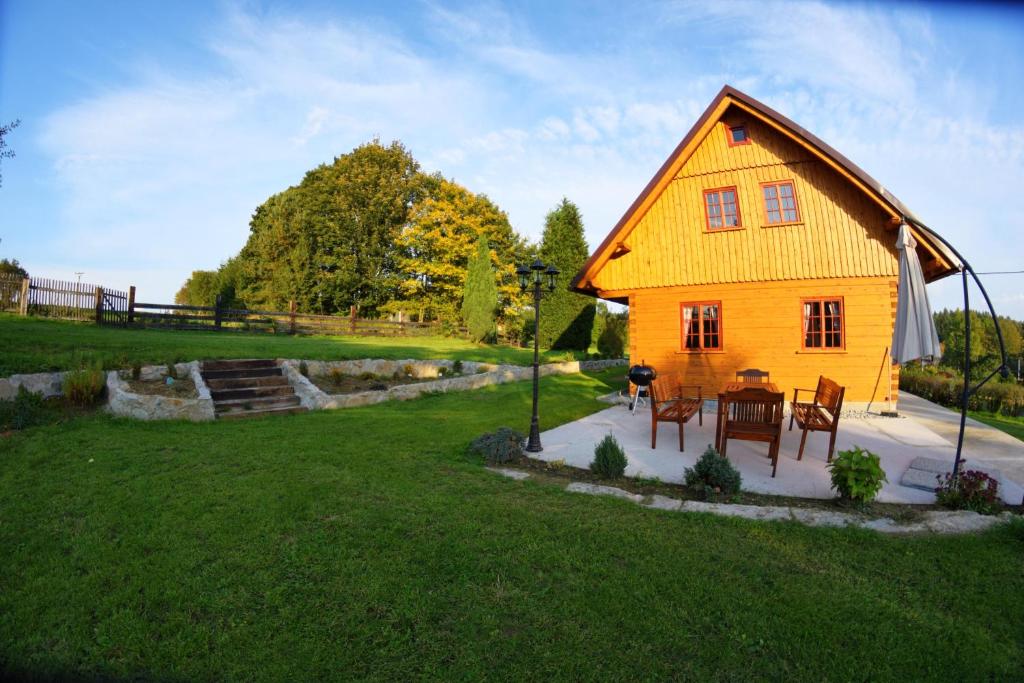 a yellow house with a table and chairs in a yard at Roubenka Háj in Jindřichovice