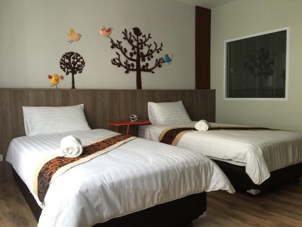 Le Lerts Living Hotel في كون كاين: سريرين في غرفة الفندق مع طيور على الحائط