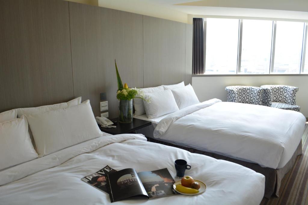 Habitación de hotel con 2 camas con sábanas blancas y un libro en de rěve Express Hotel, en Chiayi