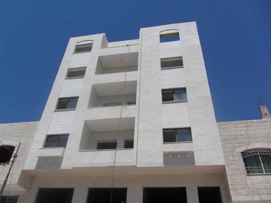 a tall white building with a blue sky in the background at Z apartment in Az Zarqa