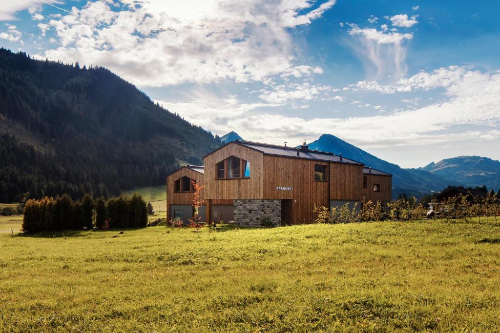 a barn in a field with mountains in the background at Chalets Gränobel in Grän