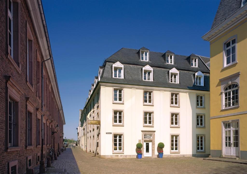 a large white building with a black roof on a street at Boutique Hotel Orangerie in Düsseldorf