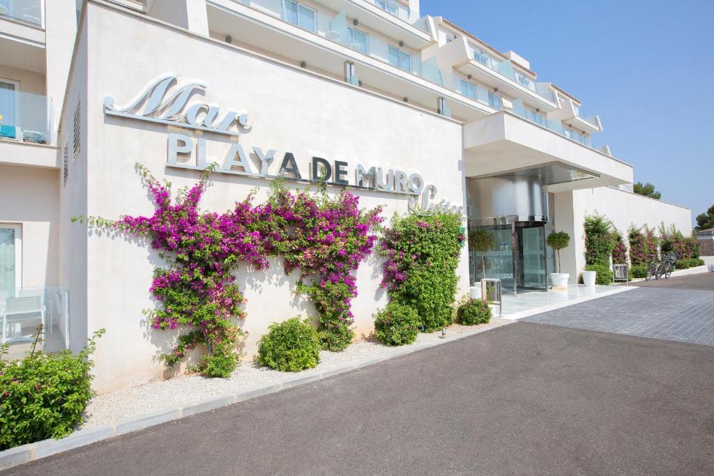 un edificio con dei fiori sul lato di Mar Hotels Playa de Muro Suites a Playa de Muro