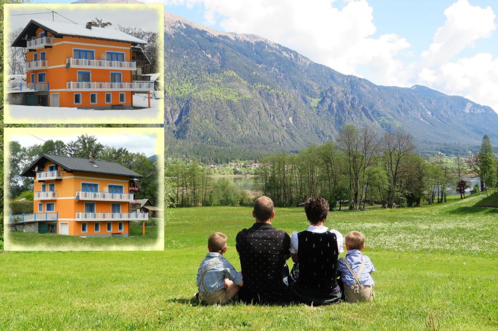 a group of people sitting in a field looking at a house at Haus Manuela am Pressegger See in Egg