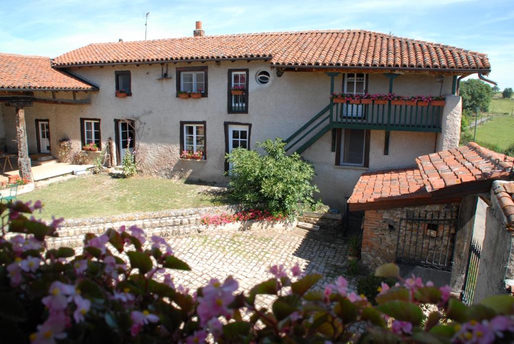 a large white house with a balcony and flowers at Chez Jacotte et Elia in Saint-Galmier