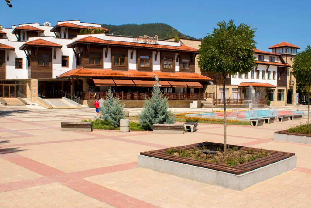 um edifício com um pátio com uma árvore e bancos em Hotel Etropolia em Etropole