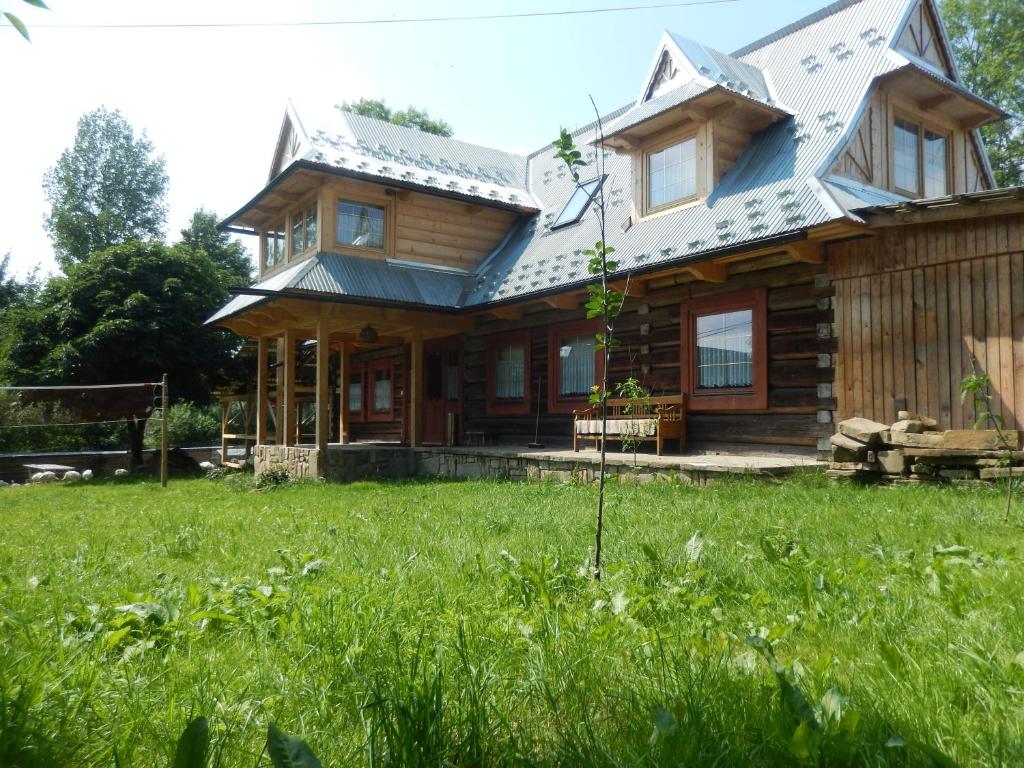 ein Holzhaus mit einem grünen Feld davor in der Unterkunft Dom u Mniszakow Agroturystyka in Witów