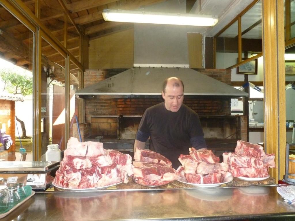 Casa Rural Irigoien في سان سيباستيان: رجل يقف خلف مكتب المحاسبة مع عدة رفوف من اللحوم