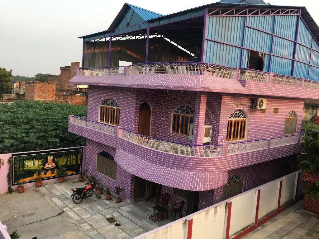 a pink building with a woman sitting on a balcony at Srishti Shelter in Varanasi