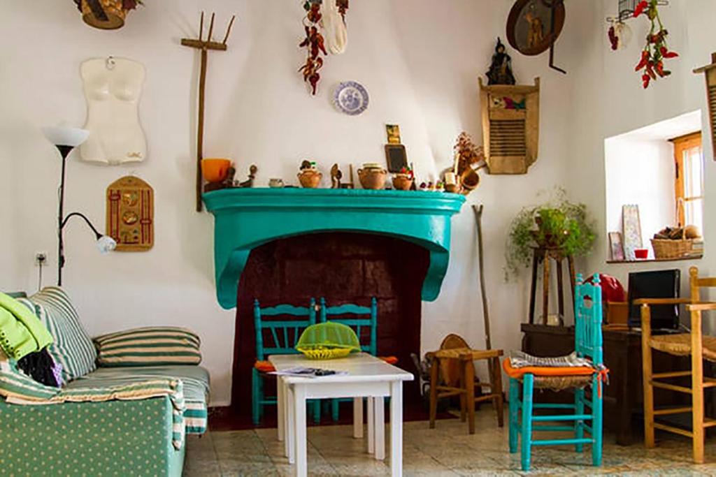 sala de estar con chimenea y manto verde en La Rana Verde Casa Rural, en Los Romeros